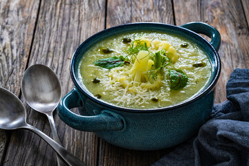 Cauliflower cream soup with Parmesan cheese served in blue rustic bowl on wooden table
