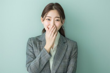 young japanese business woman covering her mouth with her hands - studio portrait