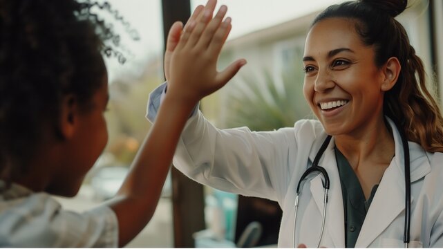Smiling female doctor give high five to little biracial patient