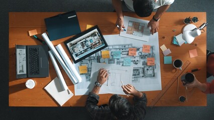 Top down view of civil engineer handed document while looking at blueprint. Aerial view of architect team brainstorming idea and planning building design while sitting at table with plan. Symposium.