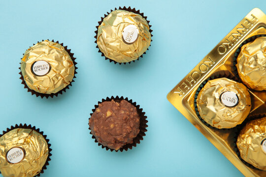 Mykolaiv, UKRAINE - July, 2024 Ferrero Rocher - round chocolates on blue background. Candy in branded packaging, a sweet pleasure for children and adults