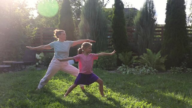 mom and child daughter do yoga in the summer garden near the house. Healthy lifestyle concept. solo outdoor activities. practice Tai Chi Chuan