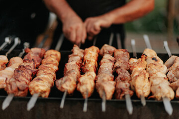 Frying shish kebab on the skewers in brazier. Fresh ruddy meat for barbecue grill on fire outdoor.