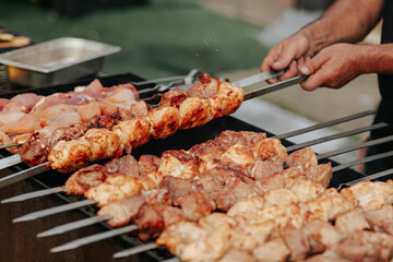 Frying shish kebab on the skewers in brazier. Fresh ruddy meat for barbecue grill on fire outdoor.