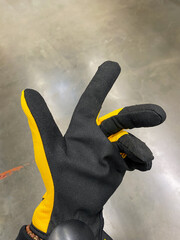 A person wears distinctive black gloves with bright yellow accents, designed for optimal protection...