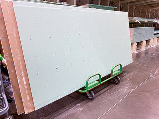 A set of Light Green Drywall Sheets placed on a Dolly Cart inside a spacious Construction...