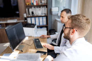 Doctors Reviewing Medical Images. Two doctors in a medical office, reviewing medical images on a...