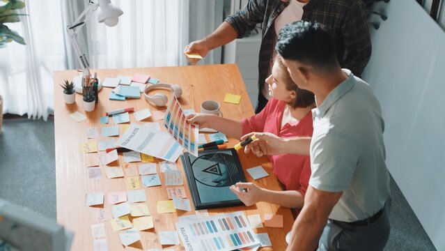Top view of smart designer holding color palette while project manager looking at design and choosing color for program. Professional businesswoman taking a note while design creative logo. Symposium.