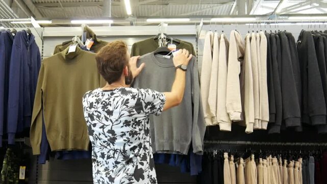 A man choosing a pullover in a clothing store