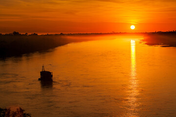 As the sun dips below the horizon, the Tambopata River is bathed in a warm, golden glow. The sky is...