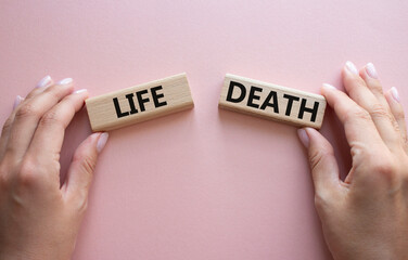 Life or Death symbol. Concept word Life or Death on wooden blocks. Businessman hand. Beautiful pink background. Business and Life or Death concept. Copy space