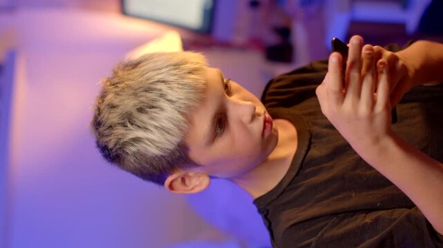 he presses the buttons device slut, reflection room, a young boy with blond hair is deeply engaged in using a smartphone