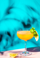 Yellow alcoholic cocktail drink with rum, liquor, grapefruit and lemon juice. Blue background, hard...
