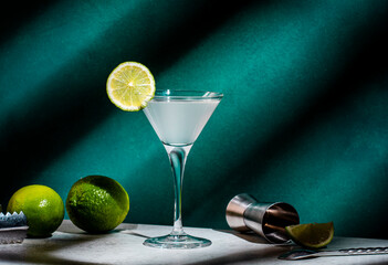 Alcoholic cocktail with vodka, syrup, lime juice and ice in martini glass, dark green background