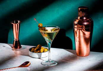 Martini, alcoholic cocktail drink with vodka, vermouth, olives on dark background, hard light