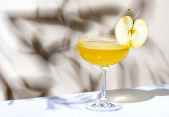 Yellow apple cocktail drink with vodka, gin, liqueur and syrup. on beige background, hard light