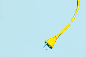 Yellow electric power cable with plug and socket on blue background.