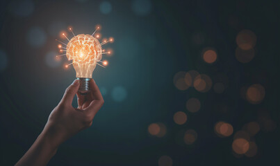 Hand holding glowing light bulb with brain icon on dark background representing innovative ideas and creativity in business technology