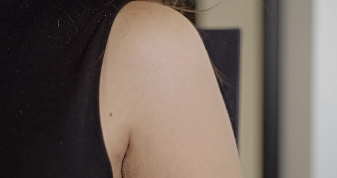 A detailed close-up of a woman's shoulder wearing a black sleeveless.