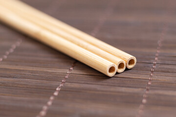 Three reusable straws on a bamboo surface. Plastic-free accessories. Environmentally friendly concept.