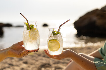 two cocktails in a glass with lemon and mint on the background of the sea