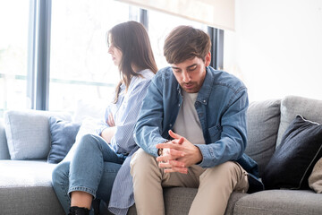 Young adult couple at home in relationship difficulties sitting on the sofa anger upset ignoring themselves. Depression and break up marriage concept. Financial problems man and woman indoor thinking