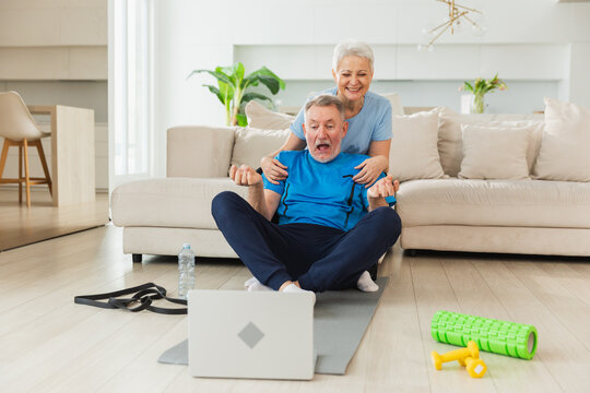 Yoga mindfulness meditation. Senior adult mature couple practicing yoga with online lessons in laptop. Old wife helping teaching husband meditating relaxing. Family doing breathing practice at home