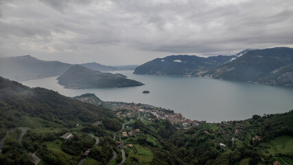 Obraz premium Majestic View Over Lake Iseo Surrounded by Rolling Hills Under Cloudy Skies