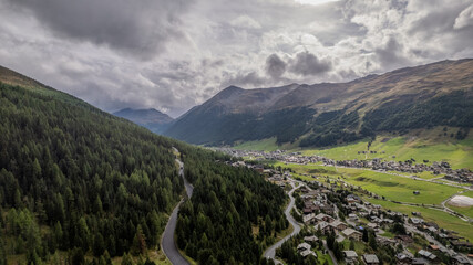 Majestic Mountain Landscape With Village Nestled in Green Valley Under Dramatic Skies