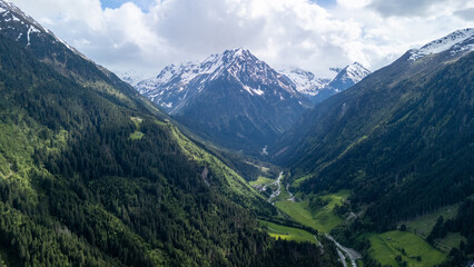 Naklejka premium Breathtaking View of Snow-Capped Mountains Surrounding a Lush Green Valley in Springtime
