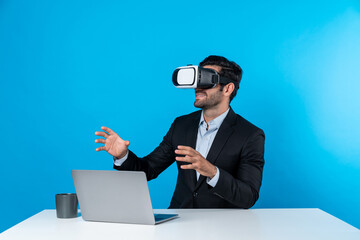 Skilled business man looking at data analysis while sitting at table with laptop and wearing VR glasses. Project manager working by using virtual reality system or connecting at metaverse. Deviation.