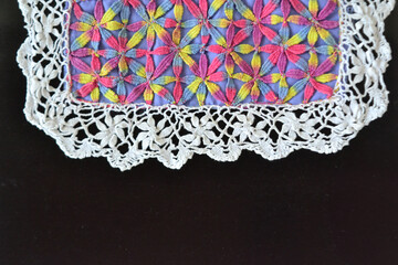 Renda de bilros florida e colorida em fundo preto. Pano florado com bordado de renda nas bordas