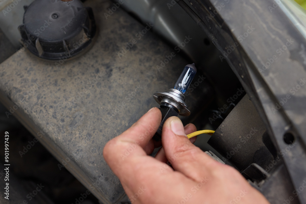Poster using hands to successfully replace headlight bulbs in a car or vehicle properly and safely