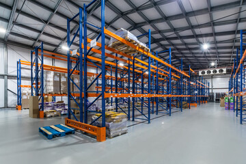 Modern Warehouse Interior Featuring Tall Shelving Units and Stored Goods. This spacious warehouse...