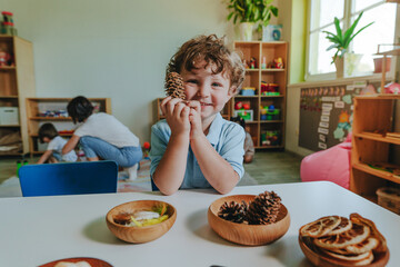 Boy playing with natural material in kindergarten or educational daycare centre