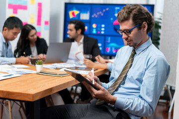 Portrait of businessman or analyst looking at camera with his colleague analyzing data analysis in dynamic business strategy investment planning meeting. Meticulous