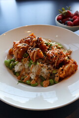 Orange chicken and rice dish with a side bowl of mixed berries