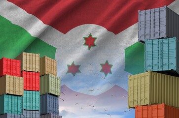 Burundi flag and big stack of shipping cargo containers in docks with sky background close up