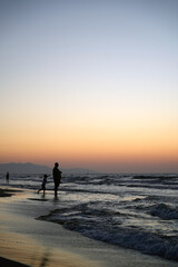 Serene beach sunset with family silhouette bonding by tranquil sea perfect for themes of peace and togetherness