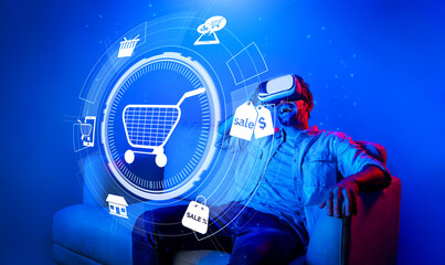 Happy man using VR headset and shopping online while sitting at sofa with shopping bags. Smart person looking at online market hologram and icon with neon background. Innovation technology. Deviation.