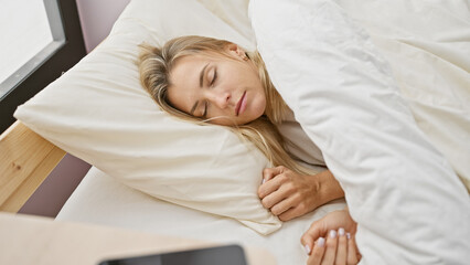 A serene young woman sleeps comfortably in a bright bedroom, epitomizing tranquil rest and cozy domesticity.