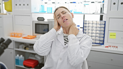 A stressed woman scientist experiencing neck pain in a laboratory setting
