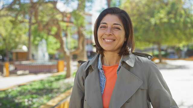 Portrait of a smiling middle-aged hispanic woman in casual clothing outdoors, exuding confidence and happiness.