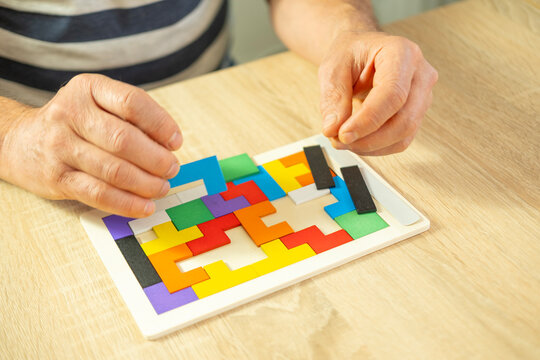male hand manipulates colorful wooden puzzle, brain health and mental well-being, cognitive health in combating dementia and Alzheimer's disease