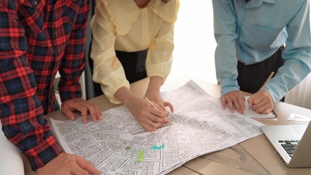 Professional engineer team discussion about house design on meeting table with architectural equipment and building blueprint scatter around at modern office. Focus on hand. Closeup. Delineation.