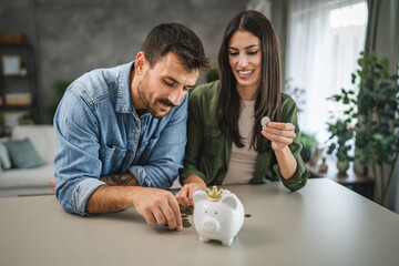 Adult couple save money coins in the piggy bank at home