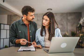 Obraz premium Adult couple work from home together on clipboard and laptop