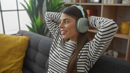 Young smiling hispanic woman relaxing with headphones in a cozy living room interior