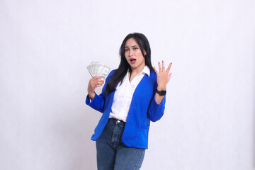 beautiful adult office woman wearing blue formal suit standing surprised to camera holding dollar bill to right and side isolated white background. for transaction, finance, business content