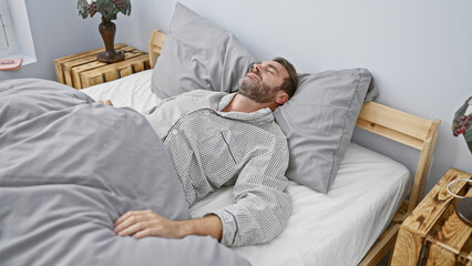 Fototapeta premium Middle-aged, hispanic man sleeping peacefully in a cozy, well-lit bedroom with modern decor